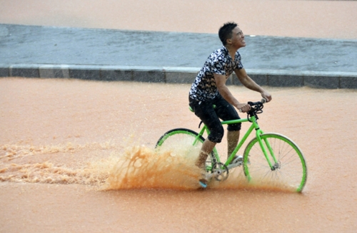 5月11日，一名行人在深圳街頭冒雨騎行。