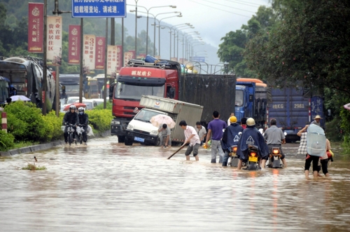 5月18日，國道324線廣西興業(yè)縣石南鎮(zhèn)黑石嶺路段被洪水淹沒，一名群眾手持木棍為摩托車探路。