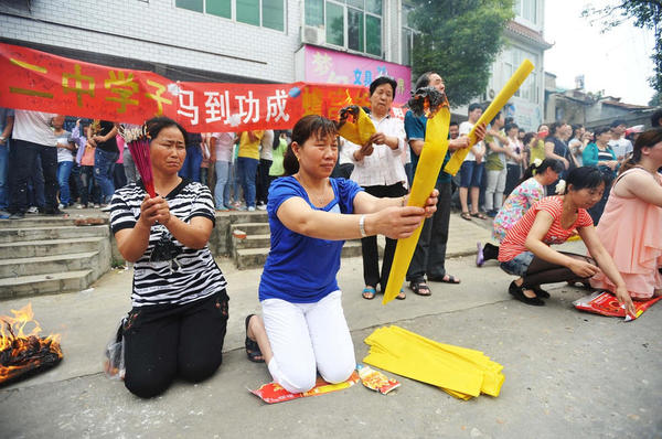 　送考家長(zhǎng)和村民燒紙跪拜。