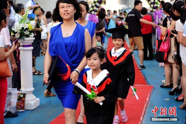 6月28日，山東青島開發(fā)區(qū)第一幼兒園怡和嘉園分園2014級大班舉行畢業(yè)典禮，全體畢業(yè)生身著學士服在盛裝父母的陪同下，依次走過紅毯，在畢業(yè)榜上鄭重簽下自己的名字，其氣勢不輸當紅影星紅毯秀。中新社發(fā) 俞方平 攝 圖片來源：CNSPHOTO