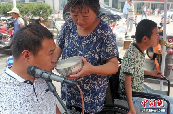 每天起床后便匆匆來(lái)到街頭“賣唱”，呂愛(ài)梅只能把面湯熬好在小強(qiáng)和小猛唱歌間隙喂他們吃。馬義恒 攝