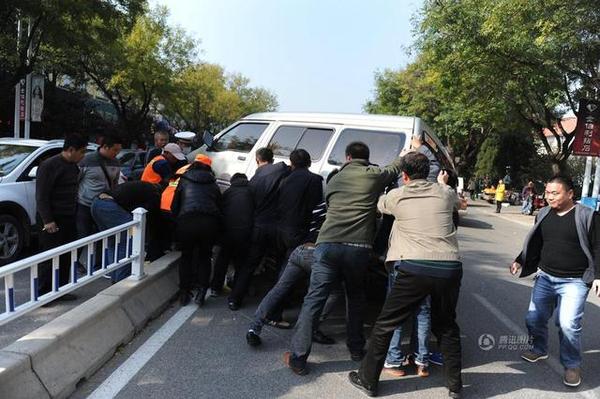 此時周圍路過的市民和附近商販紛紛趕來，十幾人用力抬起面包車，將老人救出。