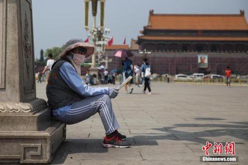 圖為在天安門(mén)廣場(chǎng)的游客，烈日下紛紛選擇各種方式降溫避暑。中新社發(fā) 熊然 攝