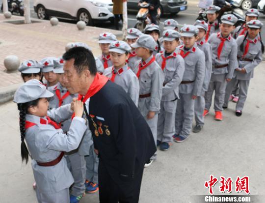 受谷殿明血雷鋒事跡的感染，雷鋒小標兵為這位“活雷鋒”爺爺系上紅領巾?！」鶊@ 攝