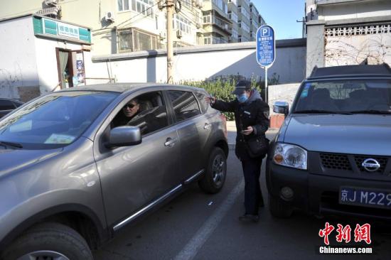 今年元月起，北京全市3000多名路側(cè)停車管理員上崗證更換，新上崗證標(biāo)有二維碼，市民用手機(jī)掃描即可看到管理員的照片、姓名、所在公司、監(jiān)督電話等詳細(xì)信息。若冒用或偽造，掃描出來的信息將與實(shí)際不符，一旦遇到假收費(fèi)員，市民有權(quán)拒絕交費(fèi)。圖為停車場管理員張大姐為車主指揮倒車。<a target='_blank' href='http://www.chinanews.com/' >中新網(wǎng)</a>記者 金碩 攝