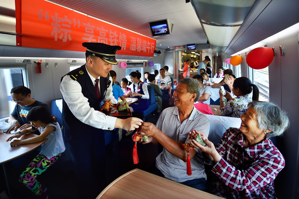 北京鐵路局天津客運段值乘的廈門北至北京南G324次列車長為老年旅客送上粽子與香囊紀(jì)念品。