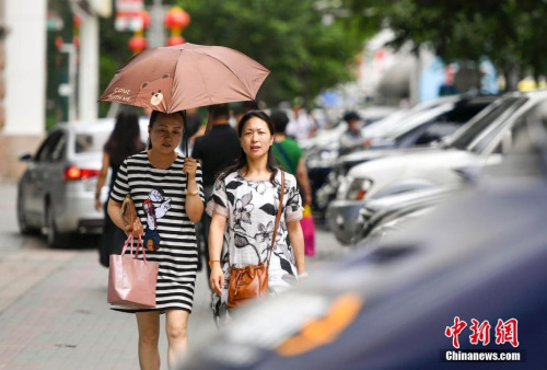 新疆烏魯木齊市街頭，民眾打傘抵擋高溫天氣。