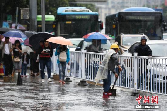 資料圖：行人在雨中出行。 黃芷昕 攝