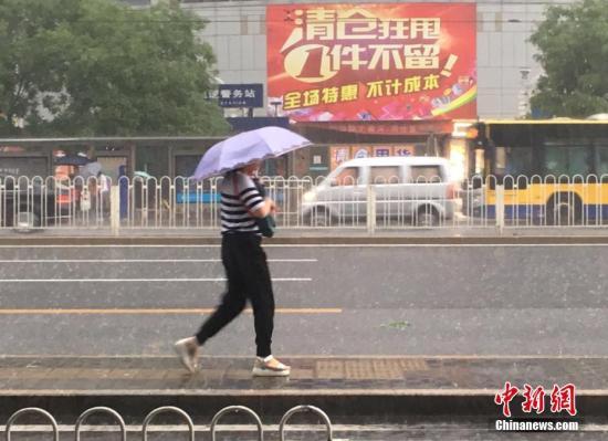 6月23日清晨，北京市民冒雨出行。 中新網(wǎng)記者 富宇 攝