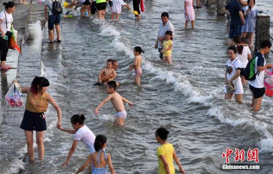 7月4日傍晚，市民們帶著小孩在海邊戲水消暑。連日來(lái)，受副熱帶高壓影響廈門地區(qū)持續(xù)高溫。 張斌 攝