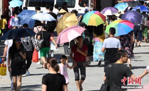 7月12日，廈門一景點(diǎn)游客們紛紛打起傘遮擋烈日。張斌 攝