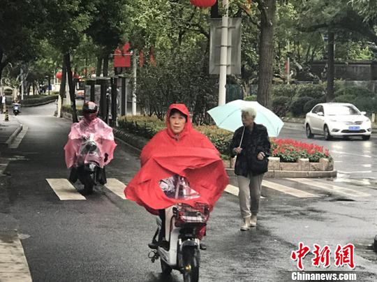 11日，南京迎來降溫降雨。圖為市民披上雨衣出行?！铑伌?攝