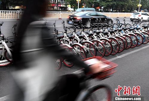 資料圖：路人騎著共享單車經(jīng)過“車堆”。<a target='_blank' href='http://www.chinanews.com/'>中新社</a>記者 張斌 攝