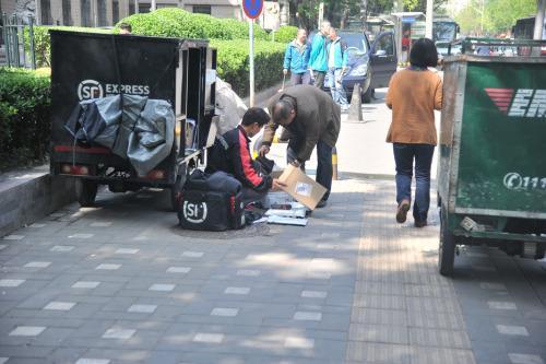 圖為快遞小哥在路邊配送快遞。呂春榮 攝