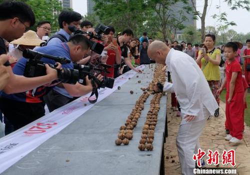 黎偉軍手劈核桃現(xiàn)場(chǎng)吸引不少人圍觀?！〕叹皞?攝