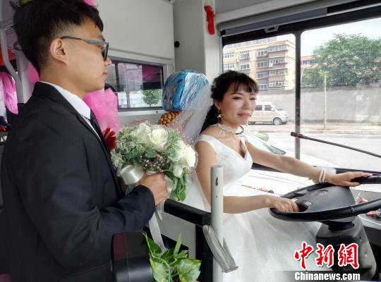 李金可駕駛公交車行駛，丈夫手捧鮮花守護(hù)在側(cè)?！≈煨?攝