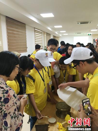 圖為華裔青少年當日在廣西自治區(qū)博物館人員的指導(dǎo)下嘗試拓印一面小的銅鼓。鐘建珊 攝