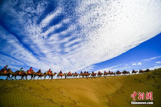 資料圖：甘肅敦煌鳴沙山月牙泉景區(qū)藍天、白云、黃沙相映成趣，每天吸引數(shù)萬中外游客觀光游覽。 王斌銀 攝