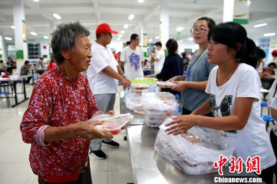 8月24日，志愿者在濰坊壽光市營里鎮(zhèn)第二初級中學(xué)安置點為災(zāi)民發(fā)放救援物資?！×籂?攝