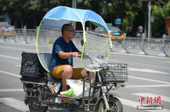 資料圖：男子在電動(dòng)車上撐起遮陽棚。<a target='_blank' href='http://www.chinanews.com/'>中新社</a>記者 劉文華 攝