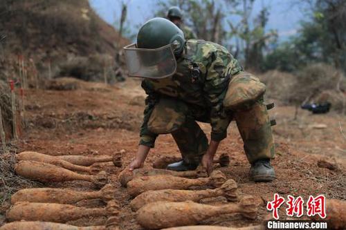 中國人民解放軍南部戰(zhàn)區(qū)陸軍云南掃雷大隊在雷場掃雷期間，一名戰(zhàn)士將一枚搜排出來的炮彈放至臨時存放點?！蠲?攝