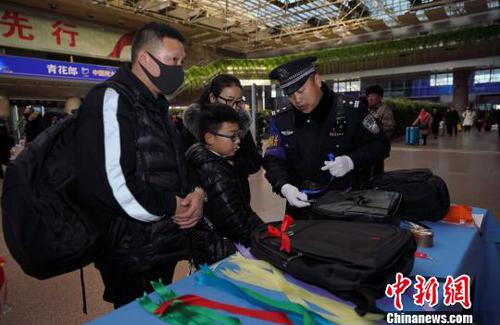 12月28日，北京西站派出所民警為背黑色雙肩包的旅客系上個性小標識，以防在通過安檢或乘車過程中出現(xiàn)錯拿情況。(完) 龐賀雷 攝