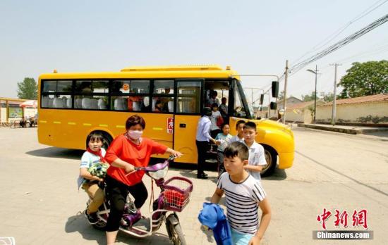 資料圖：學(xué)生家長接送從校車上下來的學(xué)生。 張道正 攝