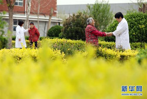 5月5日，在河北省衡水市桃城區(qū)一家養(yǎng)老康復(fù)醫(yī)療中心，護(hù)工在陪老人散步。新華社記者 牟宇 攝