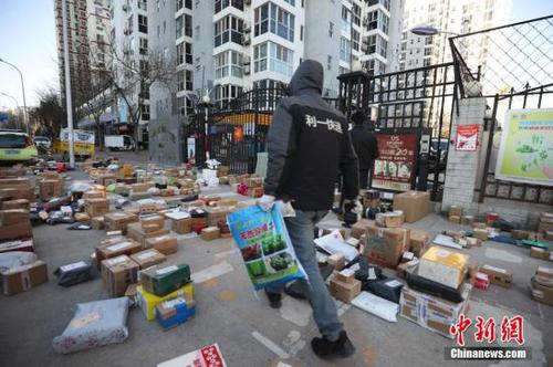 3月3日，北京朝陽(yáng)區(qū)一小區(qū)門口，快遞員為居民查找搬運(yùn)快遞物品。受疫情影響，許多市民“宅”在家中，網(wǎng)購(gòu)成為消費(fèi)主流，而線上下單量也隨之呈現(xiàn)爆發(fā)式增長(zhǎng)，不少小區(qū)門口出現(xiàn)快遞物品扎堆的現(xiàn)象。<a target='_blank' href='http://www.chinanews.com/'>中新社</a>記者 趙雋 攝