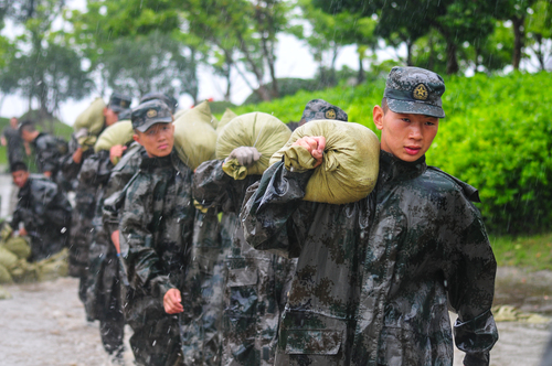 圖為在安徽合肥巢湖任務區(qū)官兵在暴雨中扛運沙袋，加固堤壩。（王文洲 攝）