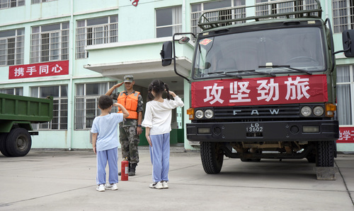 圖為在學校宿營點，小學生向抗洪官兵官兵敬禮表達謝意的畫面。（付少旋）